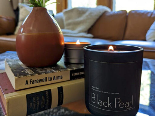 Two lit candles sitting next to a stack of books.