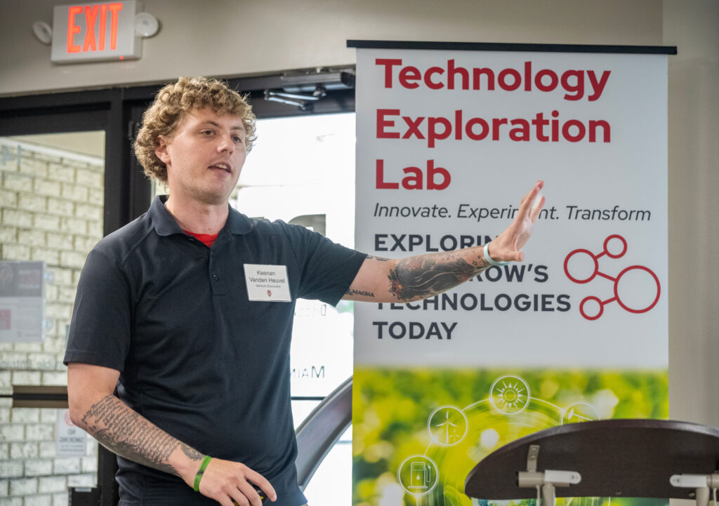 MBA student presents in front of a sign saying 