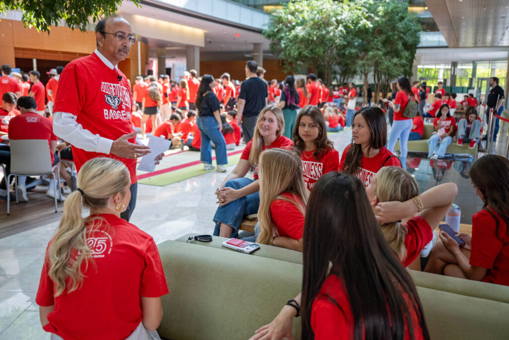 Dean Samba speaks with a group of incoming BBA students inside a large room.