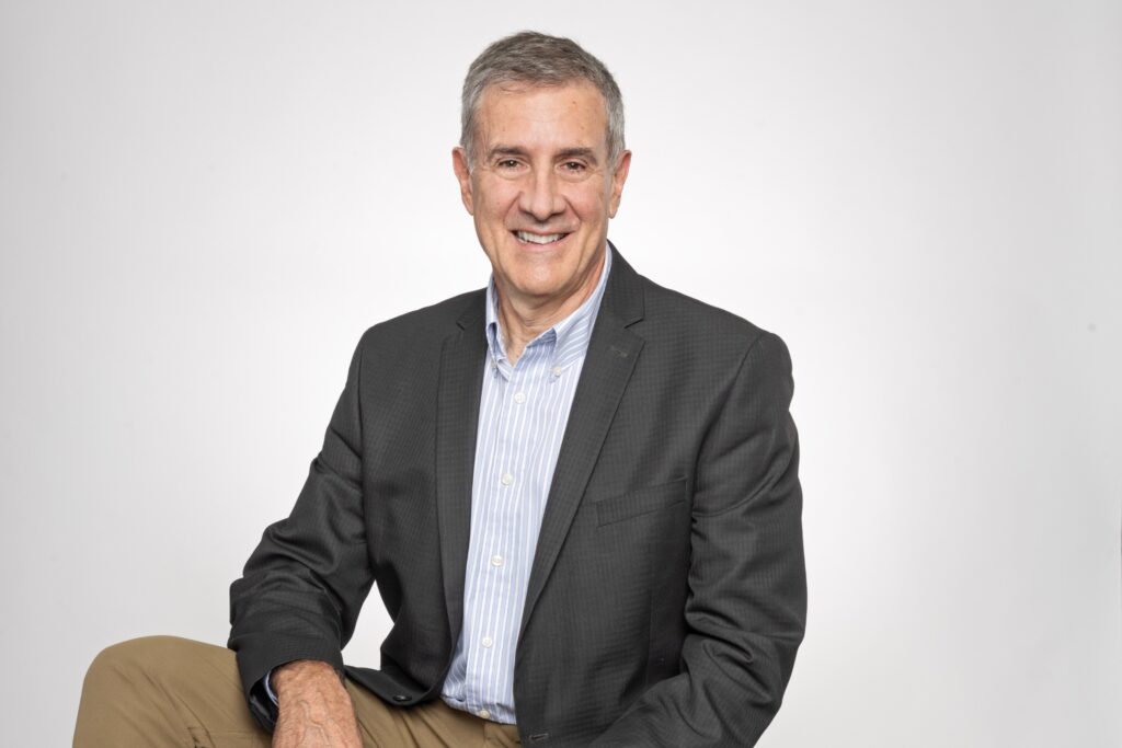 Dean Corbae seated in front of gray background.