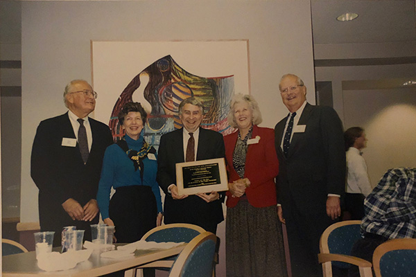 A group of faculty stand together and one holds a plaque.