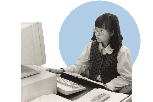 A black and white photo of a female student testing an IBM computer in 1984.