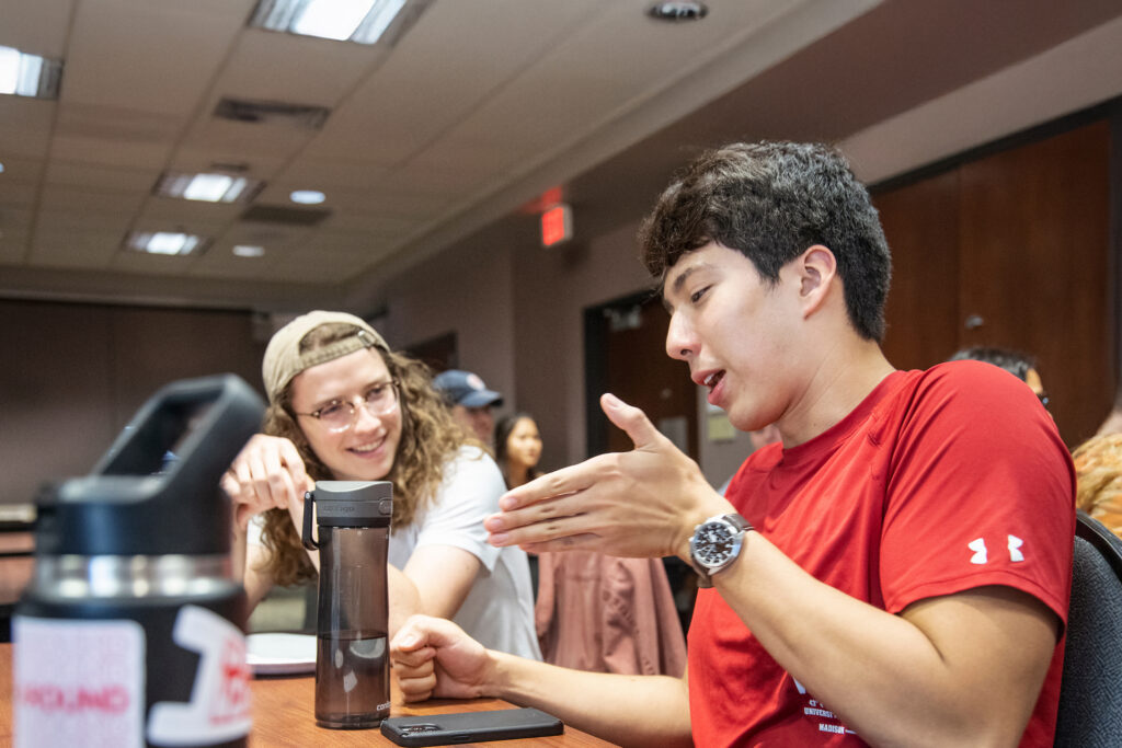 Two male students sit and have a conversation.