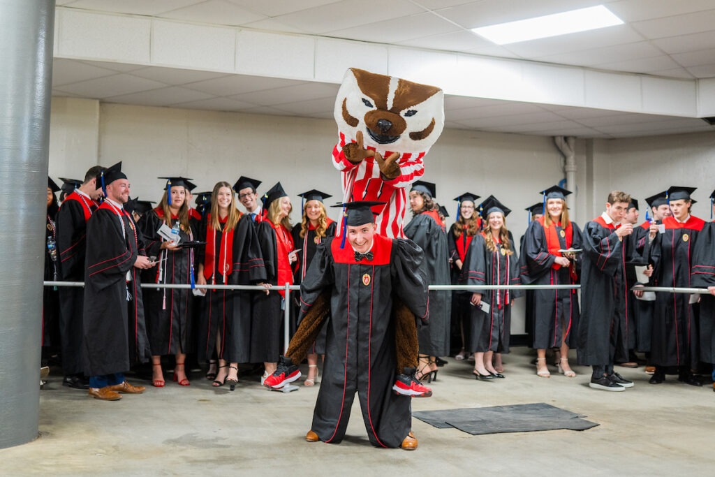 Student giving Bucky Badger a piggy back ride.