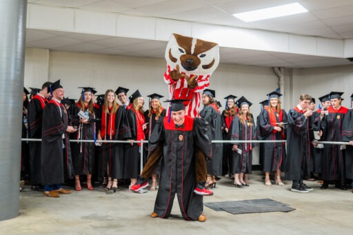 Student giving Bucky Badger a piggy back ride.
