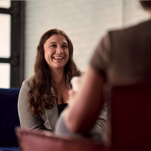 Abbe laughing as she chats with a coworker over coffee.