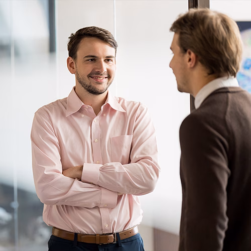 Charlie smiling as he listens to his coworker in the hallway.