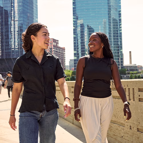 Oumou and her coworker smiling and talking as they take a walking meeting outside.