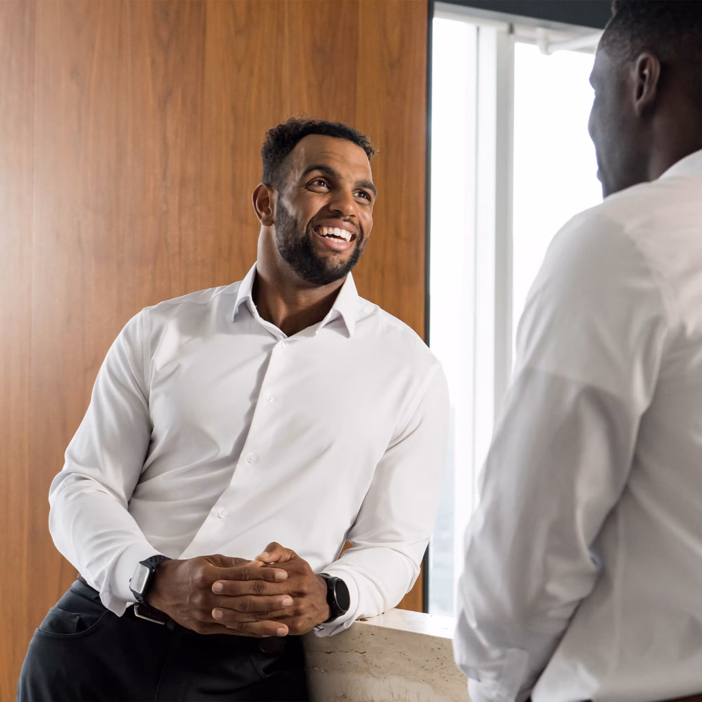 Byrson leaning against a counter and smiling as he talks to a coworker.