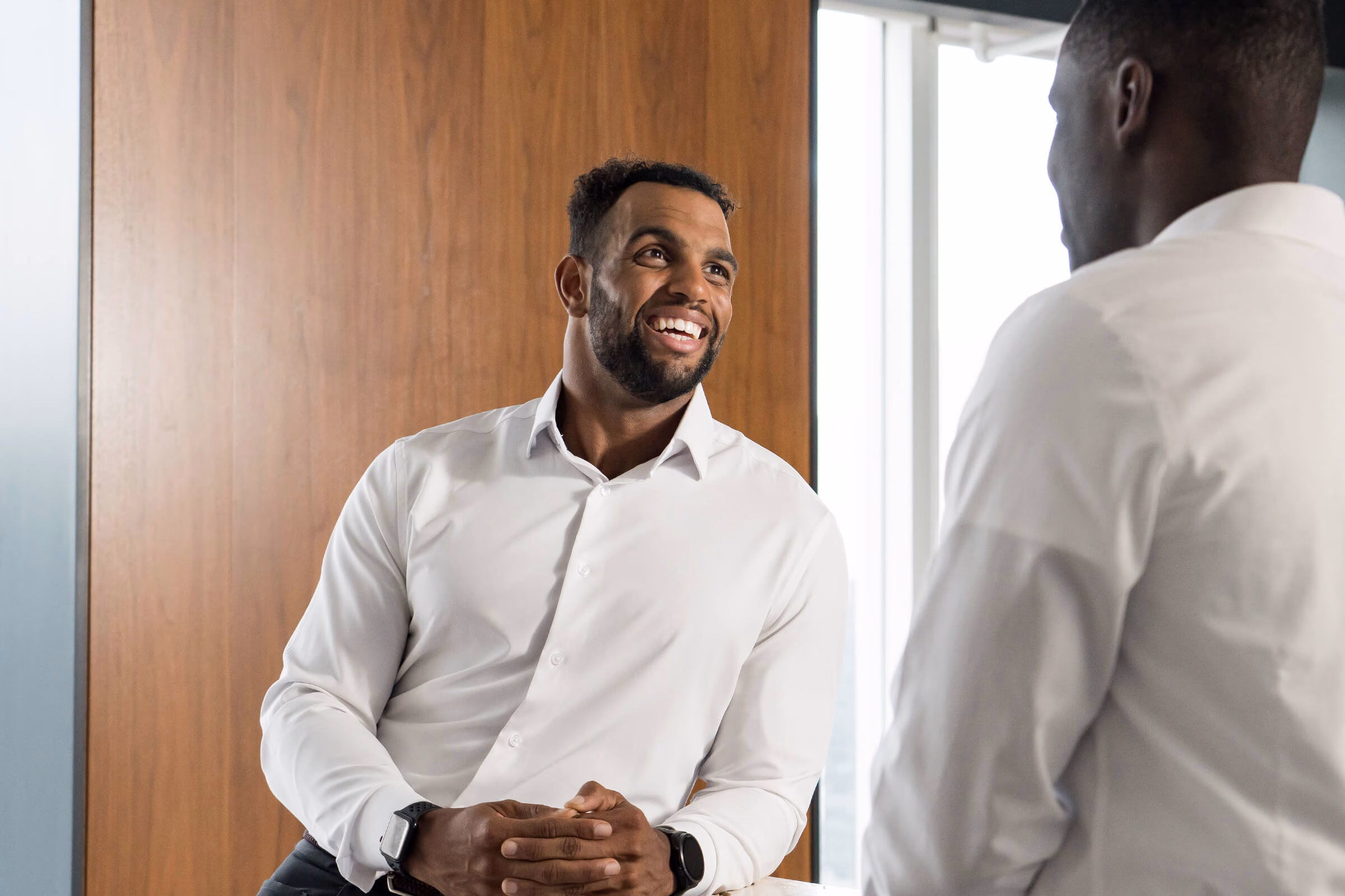 Byrson leaning against a counter and smiling as he talks to a coworker.