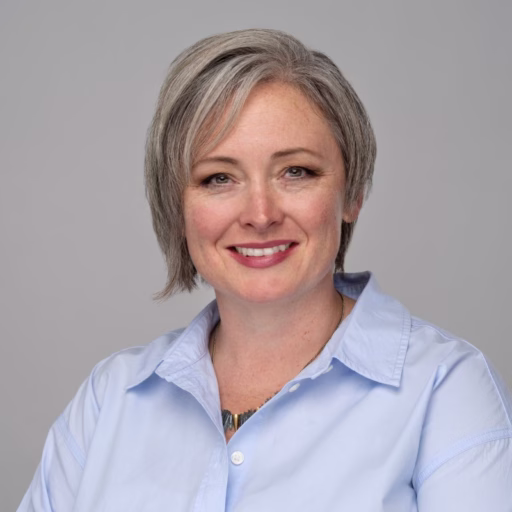 Woman with short, silver hair wearing a blue collared shirt