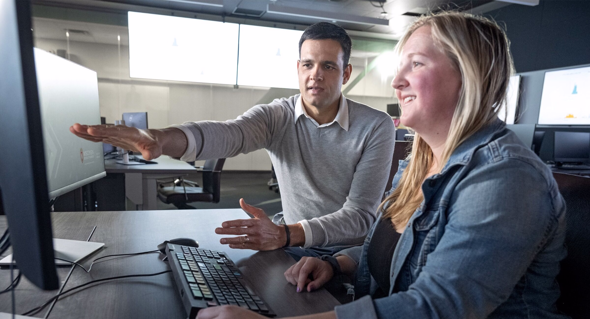 Professor Fabio Gaertner working with a student seated in front of a computer.