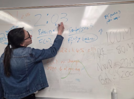 Ana is writing on a white board during a Teaching Assistant discussion.