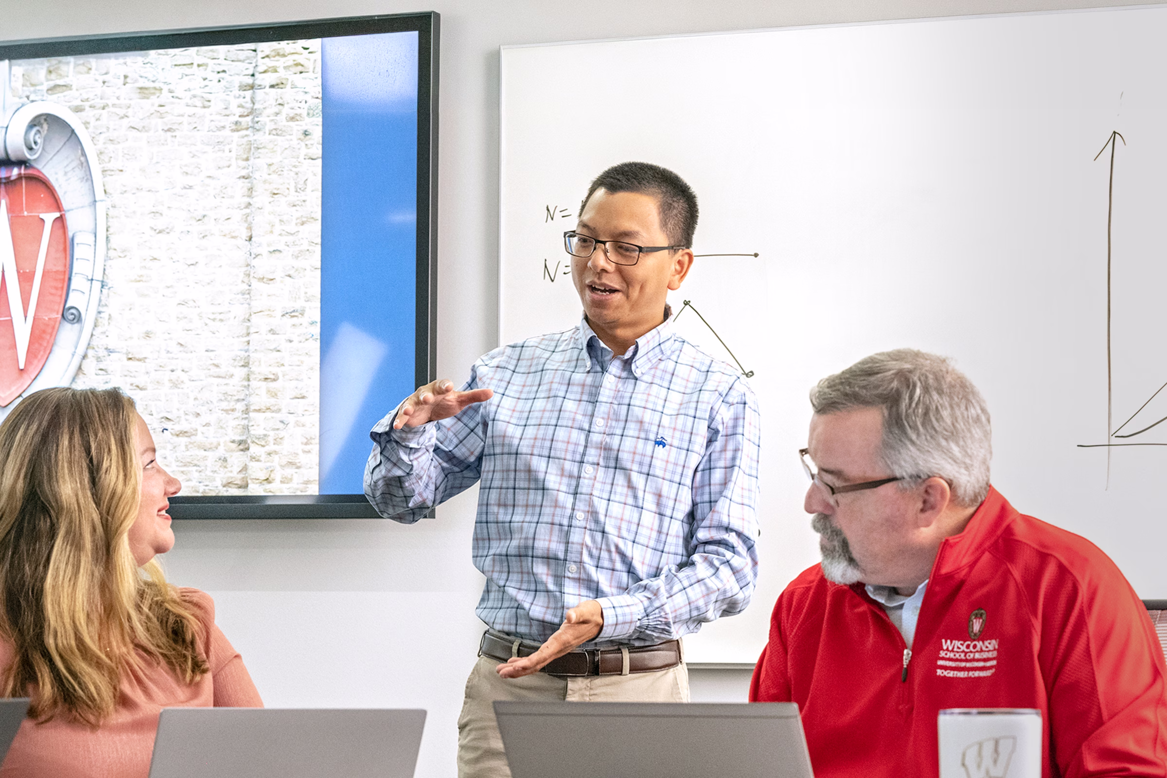 Allen Li teaches a class with two students sitting at a table in front of him.