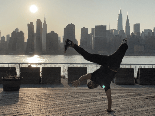Hussein Sharif doing a one-handed hand stand in front of the NYC skyline.