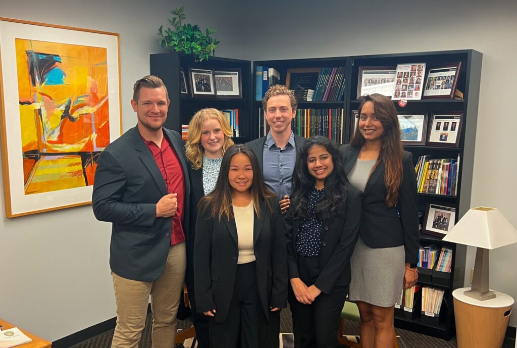 Six students are smiling and dressed in business attire before the WSB Ignite case competition.