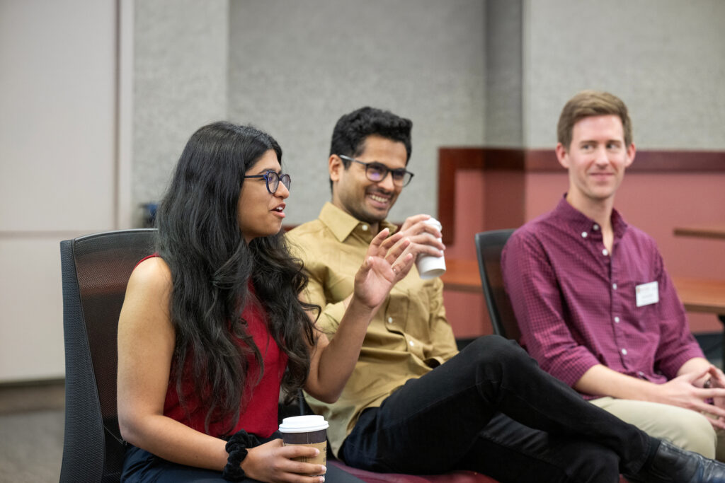 Three students laughing while sitting on chairs.