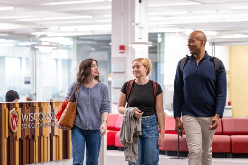 Three students walking and talking in Grainger Hall.