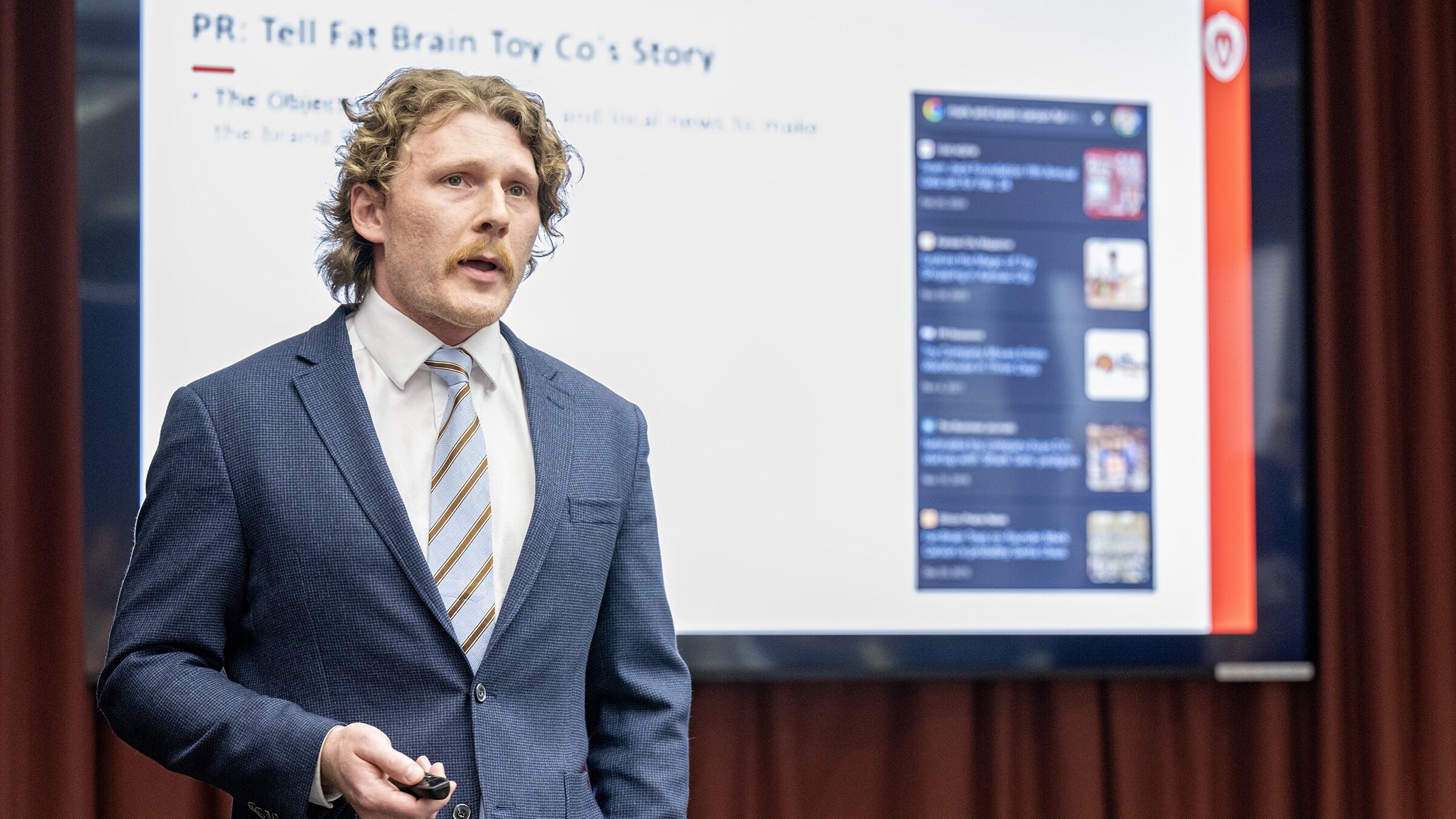 An MBA student is dressed in a business suit while presenting his project.