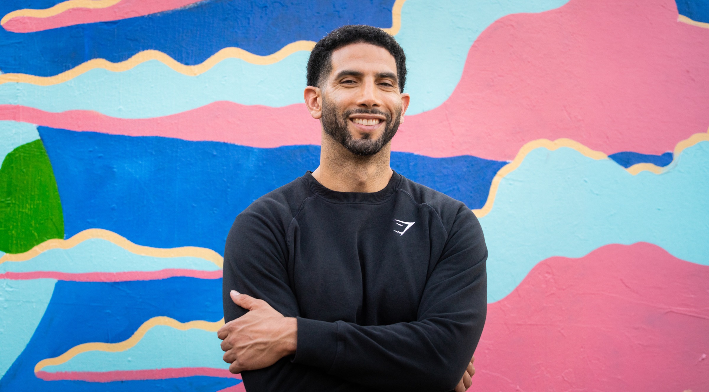 Sennai Atsbeha stands in front of a colorful mural.