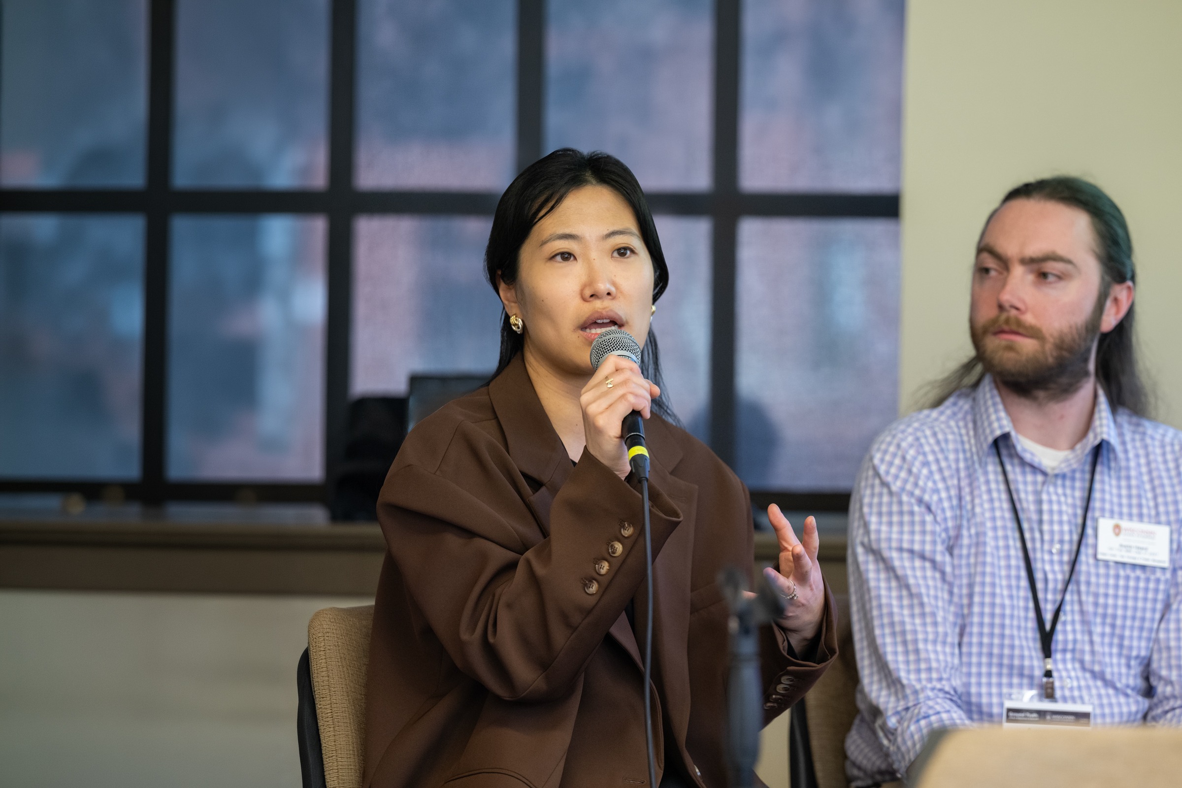 Shuting Zheng speaks into a microphone while seated next to a classmate.