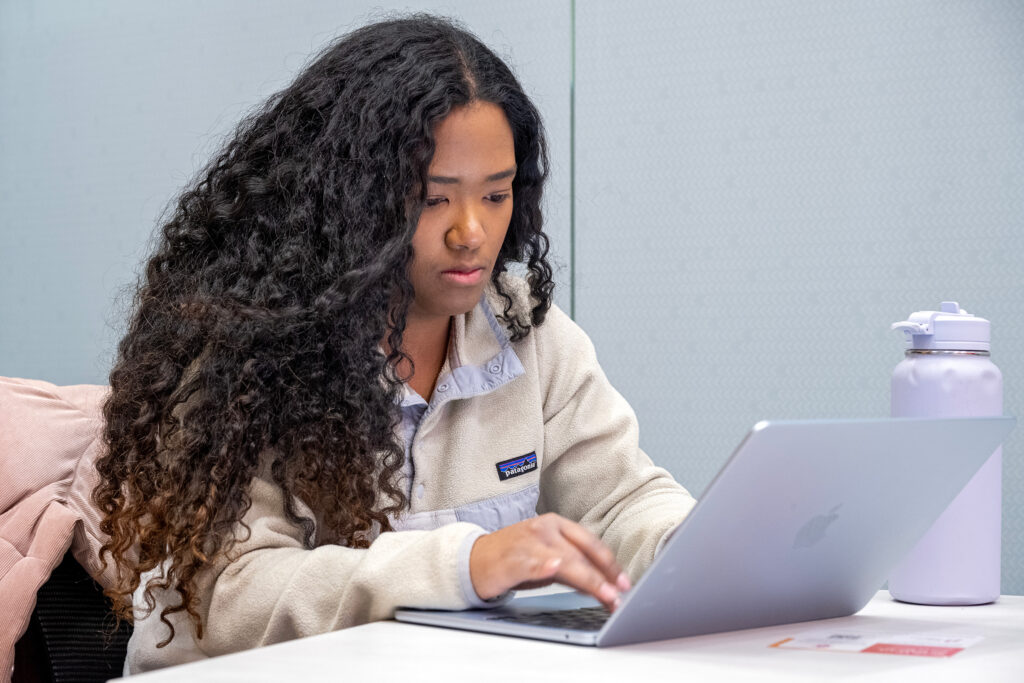 PhD student Cody-Ann Lyn focused as she works on a laptop.