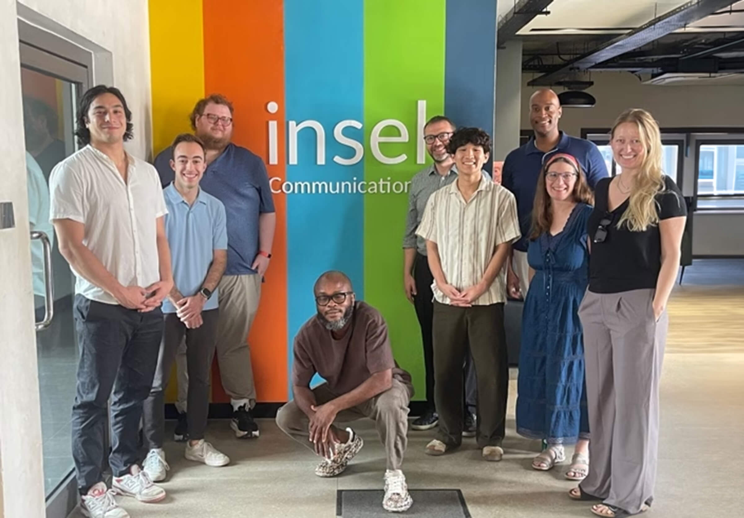 David Hadar standing with a group of people in front of a Insel Communications sign.