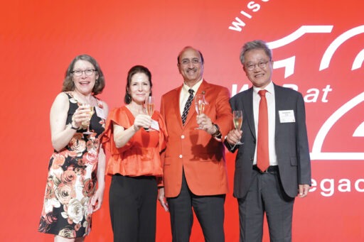 Frances Vavrus, Lora Klenke, Dean Samba, and Seoghoon Kang raise glasses in front of a red screen.