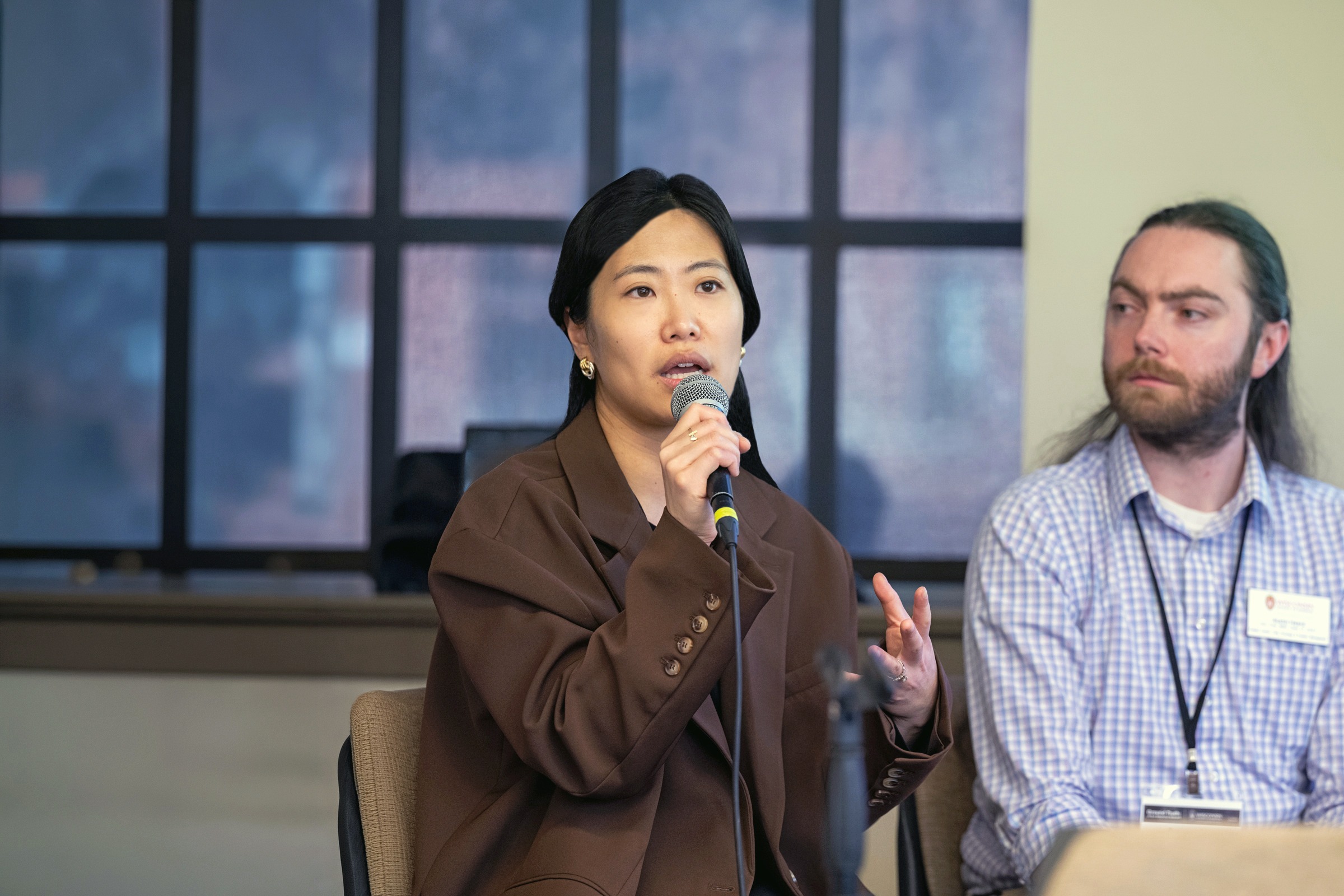 Shuting Zheng speaks into a microphone while sitting next to a classmate.