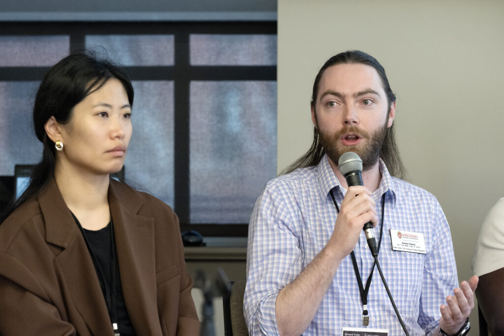White man speaking into microphone, seated next to Asian woman