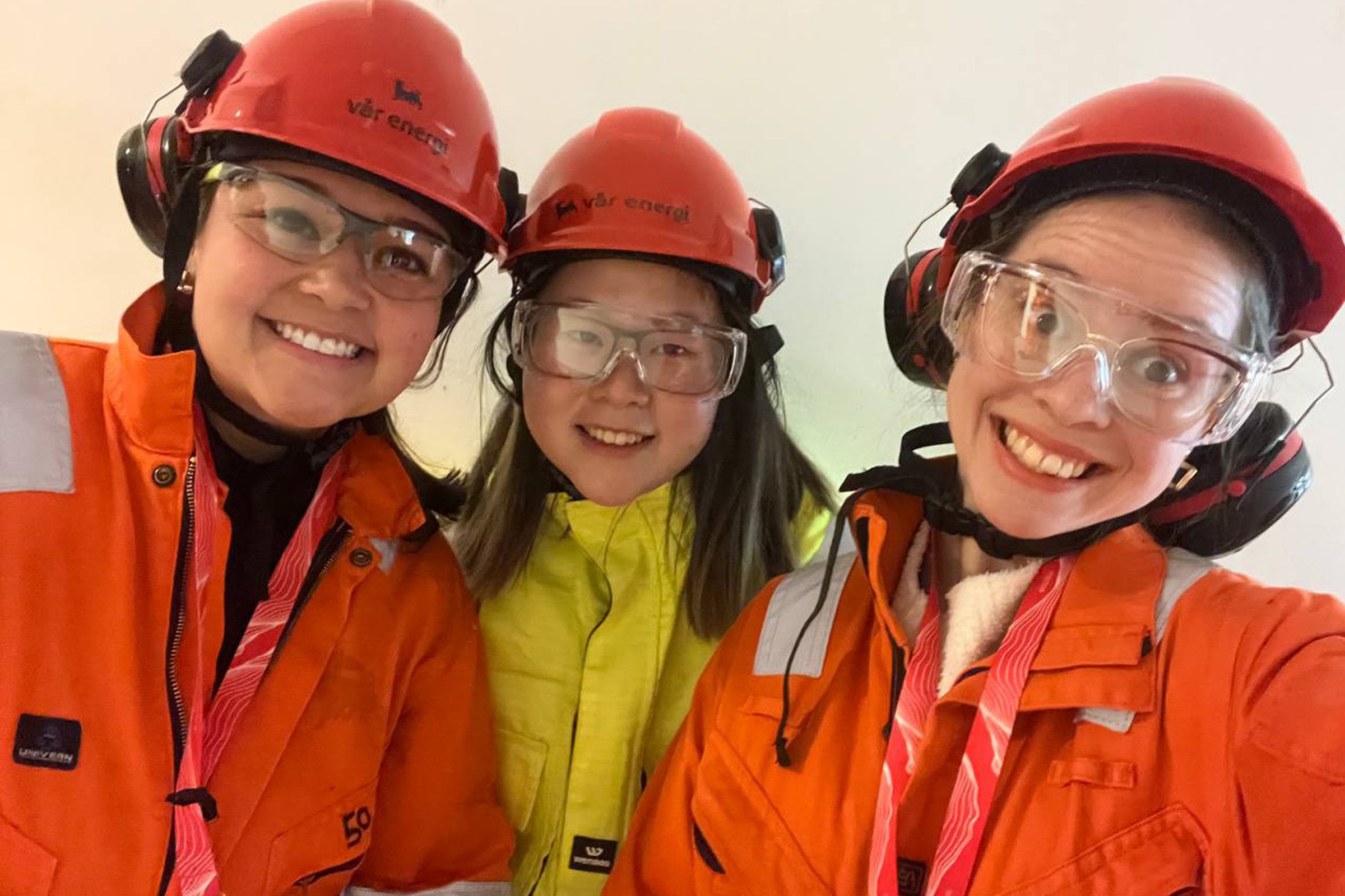 Shuang Yun Huang with two other women are wearing orange hard hats and protective glasses and coats.