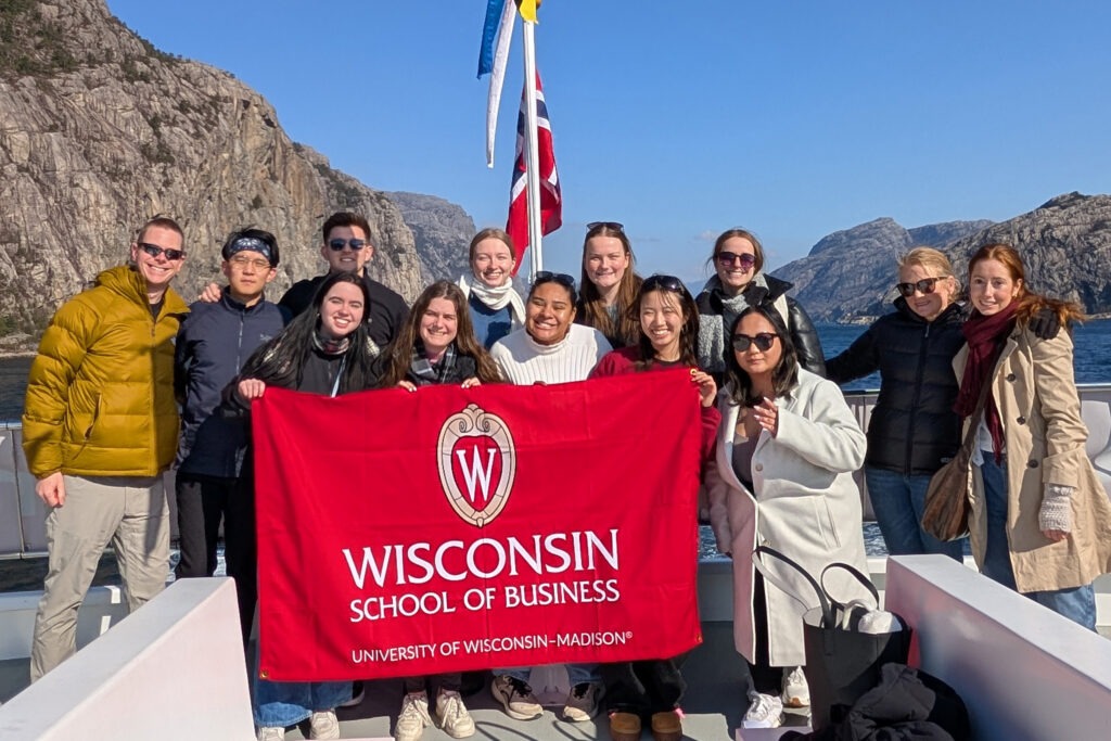 Students on a trip in holding a Wisconsin School of Business sign.