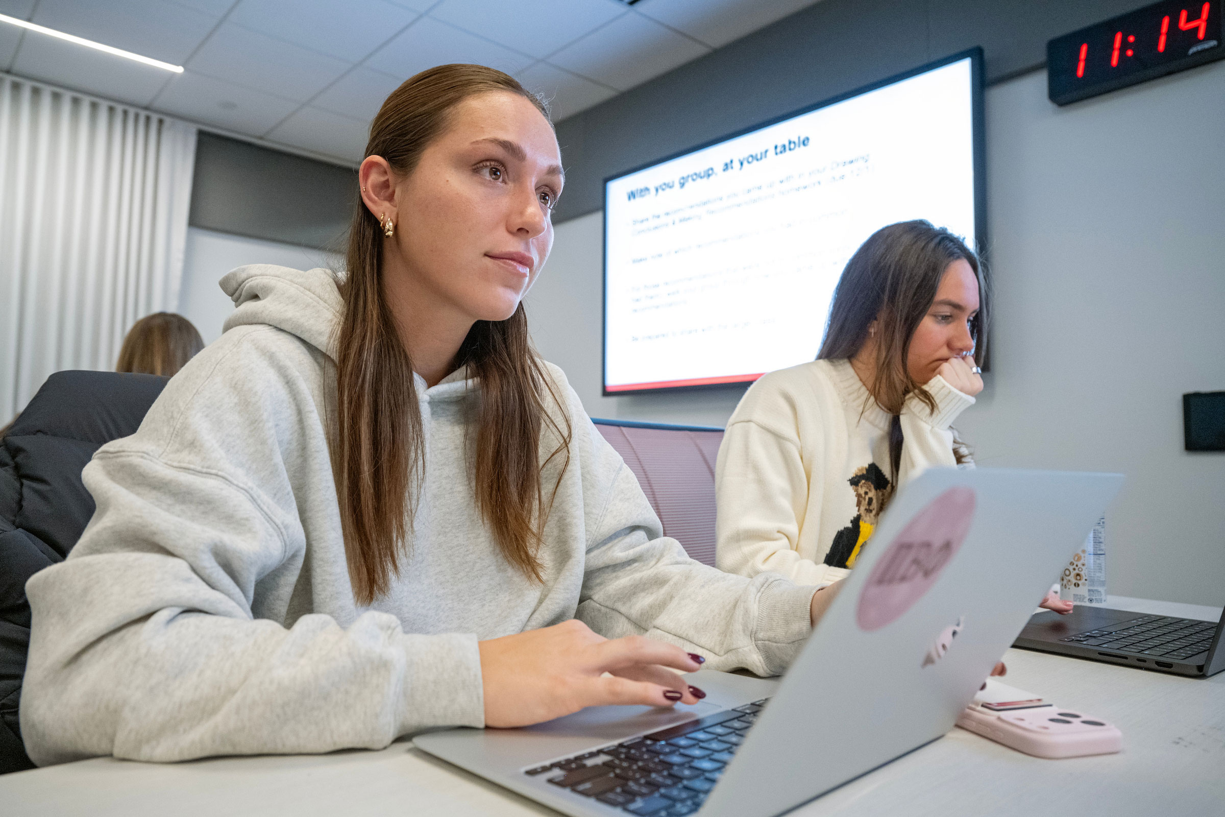 Student listening in a lecture as she takes notes on a laptop.